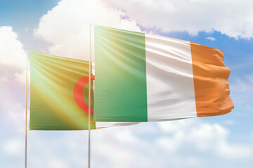 Sunny blue sky and flags of ireland and algeria