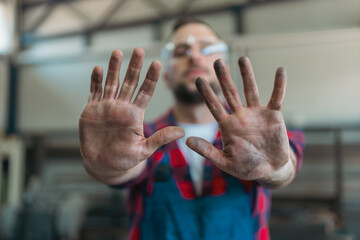 Male welder at his workplace showing of his dirty hands after successfully finishing his workday