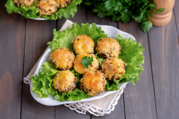 Mini Mushroom caps. Baked mushrooms stuffed with herby breadcrumbs and plenty of cheese. Wooden background, selective focus.