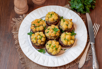 Baked Stuffed Mushrooms with mashed potatoes filling on a plate. Large brown stuffed mushrooms, ready to eat. Wooden background, top view, selective focus.