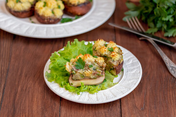 Sliced large brown stuffed mushroom with mashed potato filling. Vegan Mushrooms caps with mashed potatoes filling, portion on a plate. Wooden background, close up, selective focus.