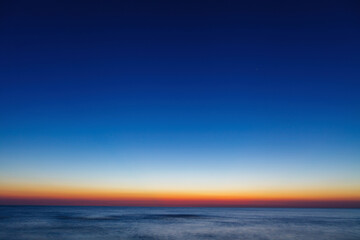 Moody sunrise over calm sea, abstract landscape