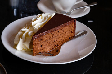 Piece of famous Sachertorte chocolate cake with apricot jam of Austrian origin served with whipped...