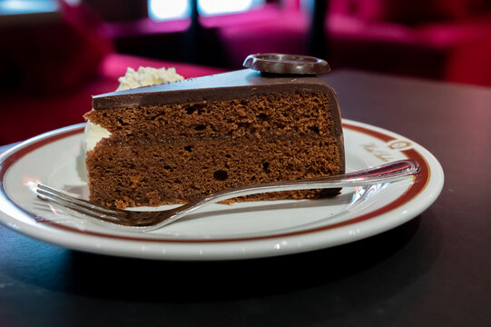 Piece of famous Sachertorte chocolate cake with apricot jam of Austrian origin served with whipped cream
