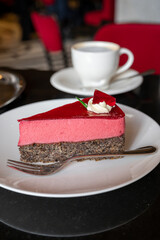 Piece of famous Poppy seed cake with raspberry mousse of Austrian origin served with whipped cream and cup of coffee
