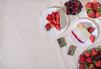Juneteenth day picnic background with Black Liberation African American flags, sweet salad with cherries and strawberries, strawberry cheesecake