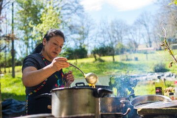 Farmer woman cooking outdoors in nature happily