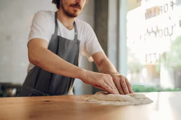 Foto auf Acrylglas Kitchen chef preparing dough for pizza while working in a pizza place © Zamrznuti tonovi