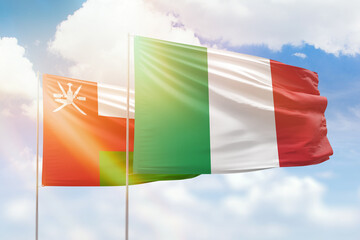 Sunny blue sky and flags of italy and oman