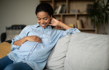 Happy Pregnant African American Woman Smiling Stroking Belly Sitting Indoor