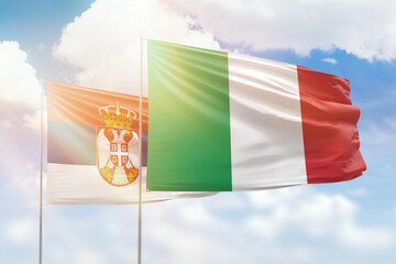 Sunny blue sky and flags of italy and serbia
