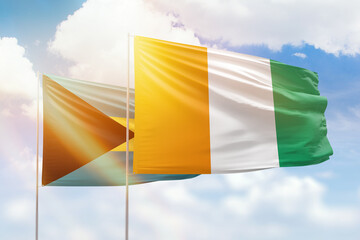 Sunny blue sky and flags of ivory coast and bahamas
