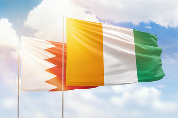 Sunny blue sky and flags of ivory coast and bahrain