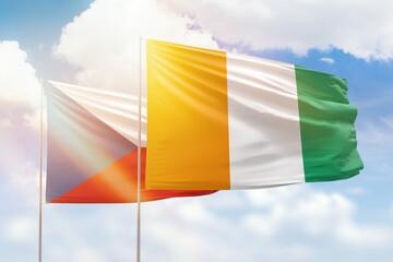 Sunny blue sky and flags of ivory coast and czechia