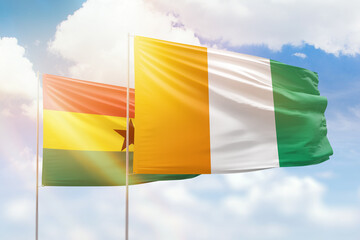 Sunny blue sky and flags of ivory coast and ghana