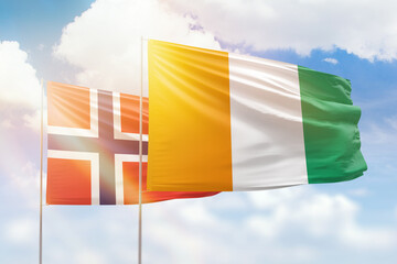 Sunny blue sky and flags of ivory coast and norway