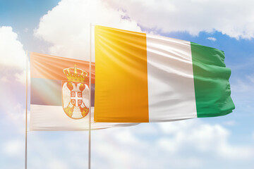 Sunny blue sky and flags of ivory coast and serbia