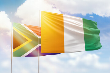 Sunny blue sky and flags of ivory coast and south africa