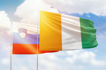 Sunny blue sky and flags of ivory coast and slovenia