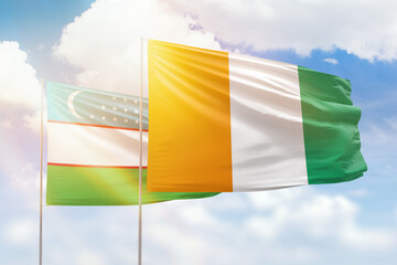 Sunny blue sky and flags of ivory coast and uzbekistan