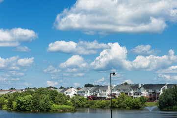 Fototapeta na wymiar Panoramic waterfront residential complex grassy lawn under cloudy blue sky