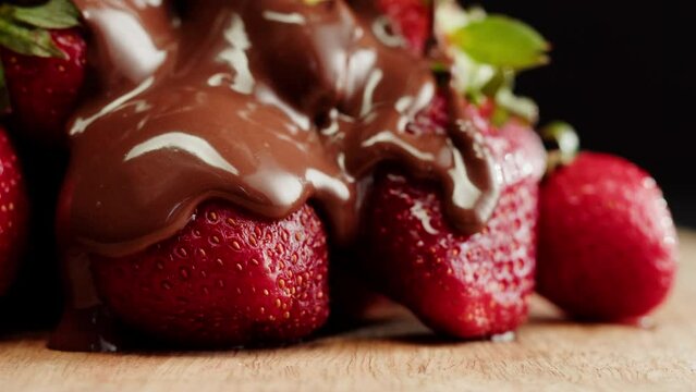 Strawberry in melted chocolate close-up, melting chocolate bar for fondue. Berries with choco mousse. Professional chef cooking cake dessert.
