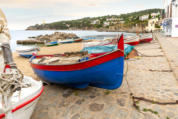 Fototapeta na wymiar Fishing boats docked and moored on the sandy beach of the Spanish village of Calella de Palafrugell, Spain, on the Costa Brava coast.