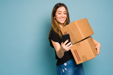 Young woman using an app on her smartphone to ship some packages in a studio