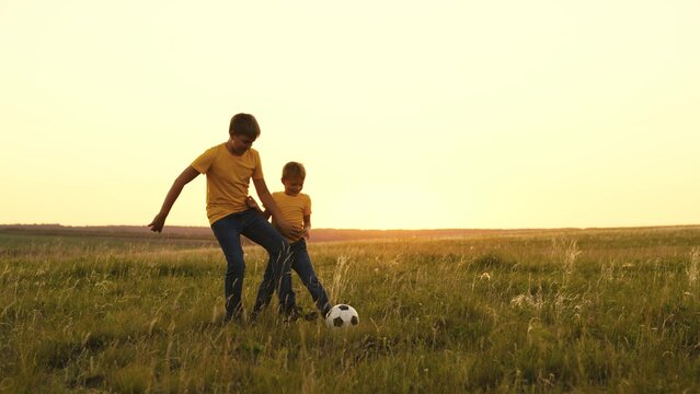happy family sunset. group people playing soccer with soccer ball. boys play football with their father. child kid run around field kick ball with their foot. children play green field with brothers.