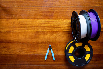 3D printing filament reels and tool s for 3d printers isolated on wooden background