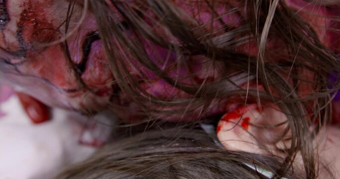 Hungry spooky man bites and eats piece of neck from victim. Zombie with mustache and blood spots on body kills and eats young woman extreme closeup