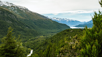View from the top of a river going through a forest and flowing into a lake in the Andes mountain range. Calihuel River Rivadavia Lake. Chubut, Argentina