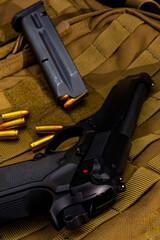 Artistic photo of a semi automatic 9mm handgun on a brown background in a tactical military setting with a loaded magazine and loose rounds of ammunition