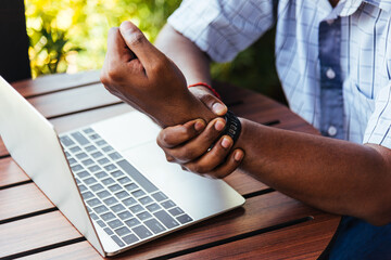 Closeup hands the Asian black man holding his wrist pain from using laptop computer he working long...