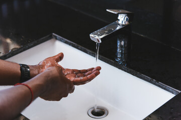 Closeup washing black man hands rubbing with soap and water in sinks to prevent outbreak...