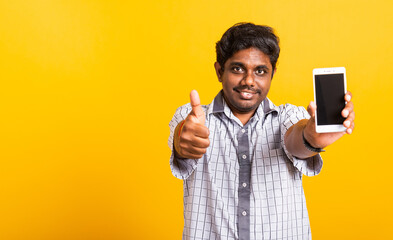 Closeup Asian happy portrait young black man smile showing a mobile smartphone blank screen and finger thumb up for a good sign, studio isolated on yellow background