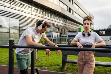 Young couple man and woman boyfriend girlfriend or husband and wife training at outdoor gym in park in day sport and recreation healthy lifestyle exercise concept real people copy space