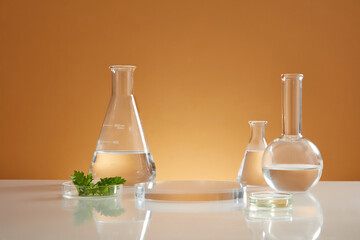 Front view of transparent podium with laboratory equipment and mugwort in brown background science content