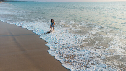 Happy Carefree Woman Enjoying holiday. Woman silhouette walking on the beach at sunset. 