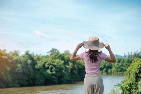 Solo Woman in pink and hat Traveling near river. Happy girl in nature. popular for tourists attractions in Kanchanaburi, Thailand