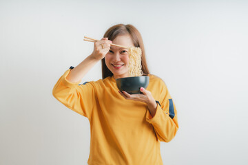 Asian girl holding a bowl of noodles with chopsticks and eating it, isolated on white background