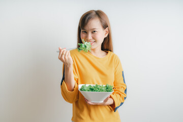 Asian woman eating a fresh salad isolated on white