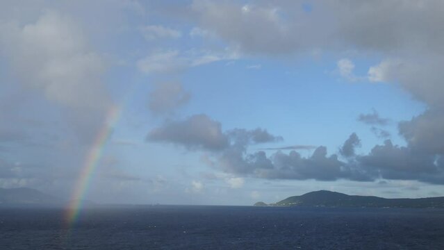 Rainbow over ocean with cloudscape and island in background