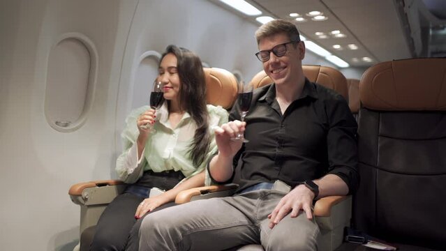 Cabin crew serving a red wine to the couple passenger.