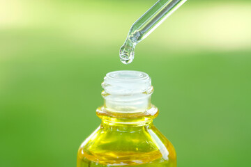 Dropping serum collagen moisturizer of face into clear yellow bottle soft light background. Protector skin Treatment facial essence oil, Vitamin C. Beauty and spa Concept.