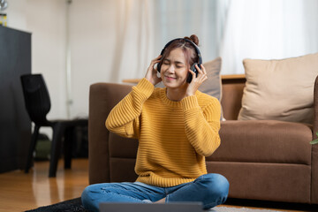 Obraz premium Young beautiful woman in yellow outfit enjoying the music at home