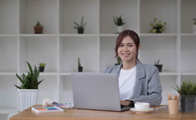 Beautiful smiling young graphic designer sitting at desk in office and working