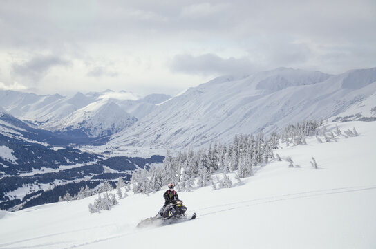 Snowmachine rider in Alaska backcountry enjoying fresh snow in winter