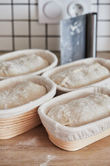 Process of making wheat bread at home. Proofing of the dough in rattan baskets. The concept of healthy homemade food. Vertical photo.