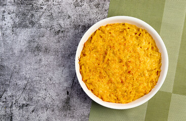 Mac and cheese, american style macaroni pasta with cheesy sauce and crunchy topping in a white baking dish on a dark grey background. Top view, flat lay